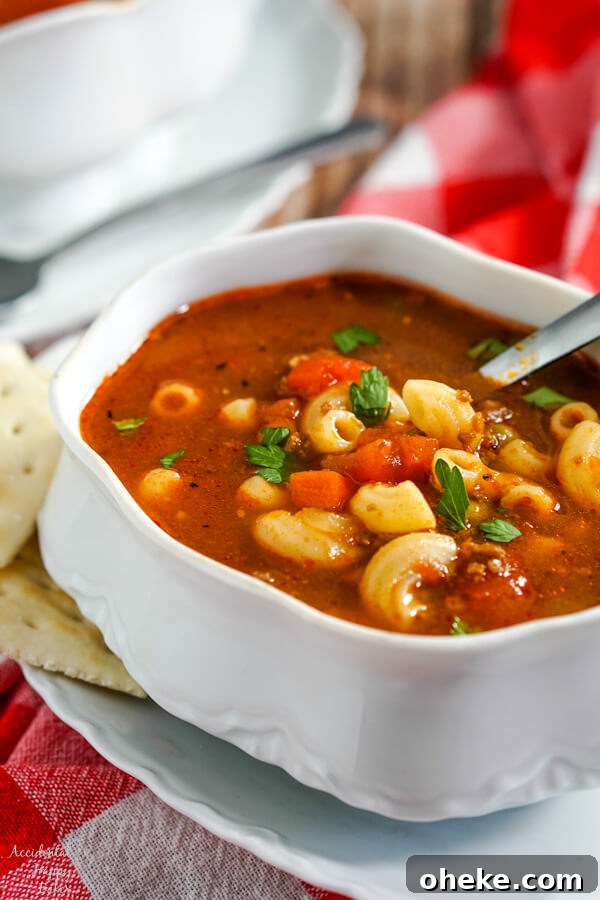 Garlic Bread Sloppy Joes: Cheesy Savory Sandwich Recipe 4 A white soup tureen full of hamburger macaroni soup with a soup spoon in the bowl and crackers to the side.