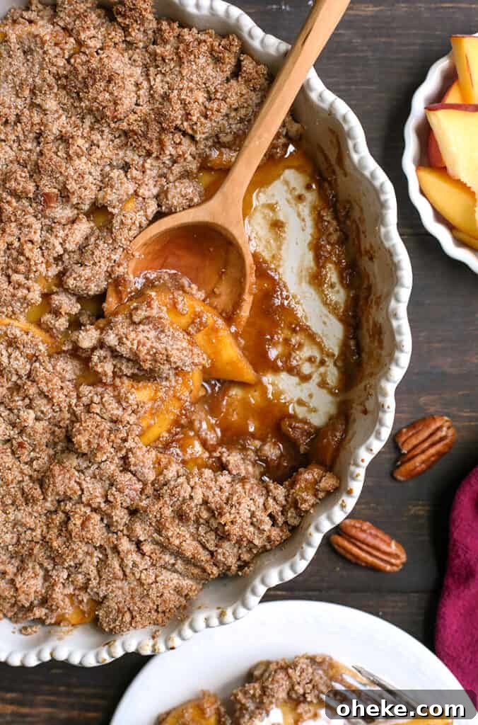 Paleo-Friendly Vegan Peach Crisp Recipe for Summer Desserts 2 paleo vegan peach crisp in a pan with a scoop taken out