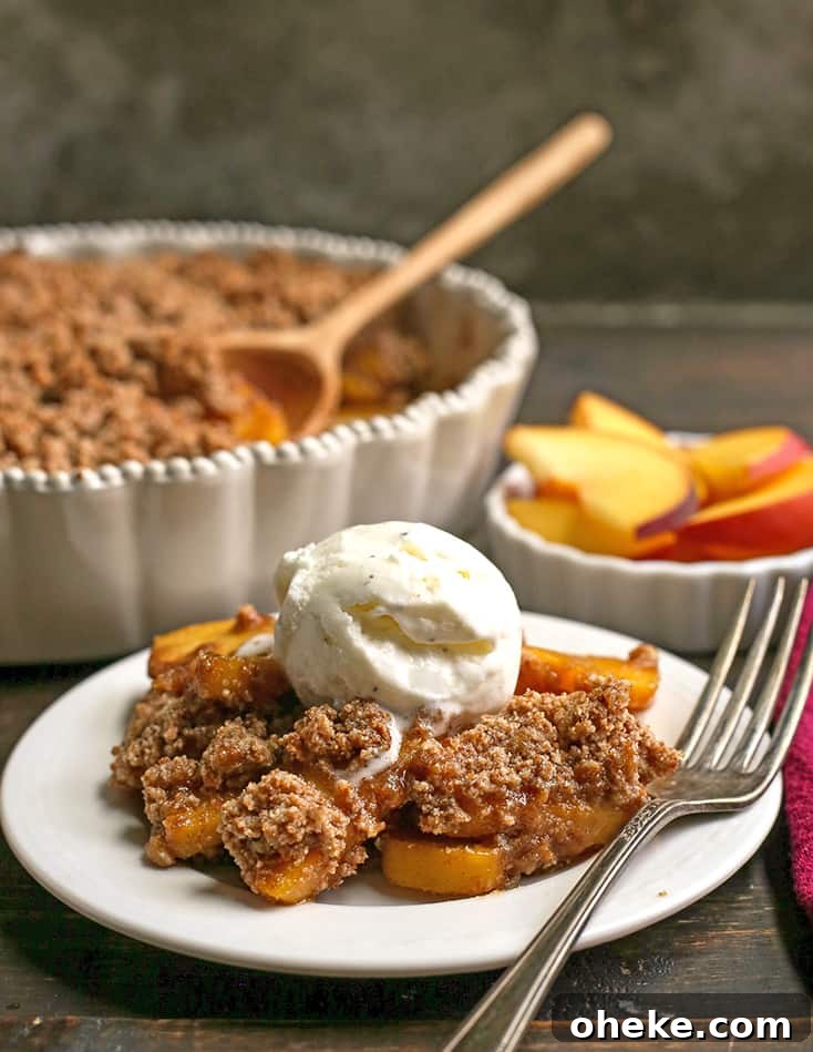 Paleo-Friendly Vegan Peach Crisp Recipe for Summer Desserts 5 side shot of paleo vegan peach crisp on a plate with ice cream