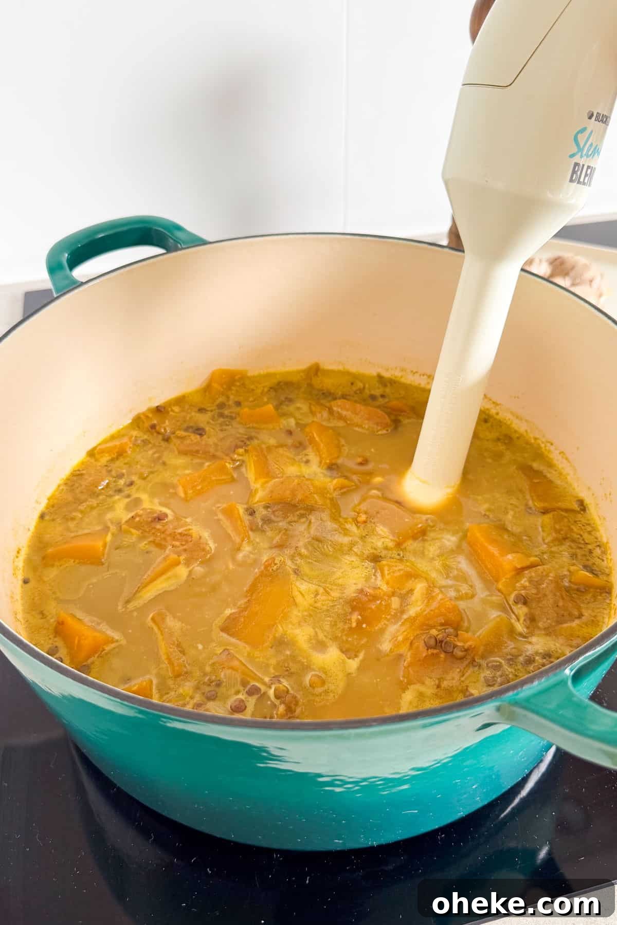 Curried Butternut Squash and Lentil Soup Recipe 7 Soup being blended with a stick blender.