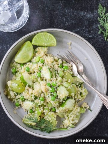Vegan quinoa salad with green veggies and fruit on a gray plate.