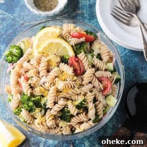 Zesty Lemon & Artichoke Pasta Salad Recipe for Summer 12 Bowl of vegan pasta salad with rotini noodles, broccoli, cucumber, artichokes, and tomatoes.