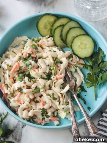 Vegan Macaroni Salad on a blue plate with two forks and a side of sliced cucumbers.