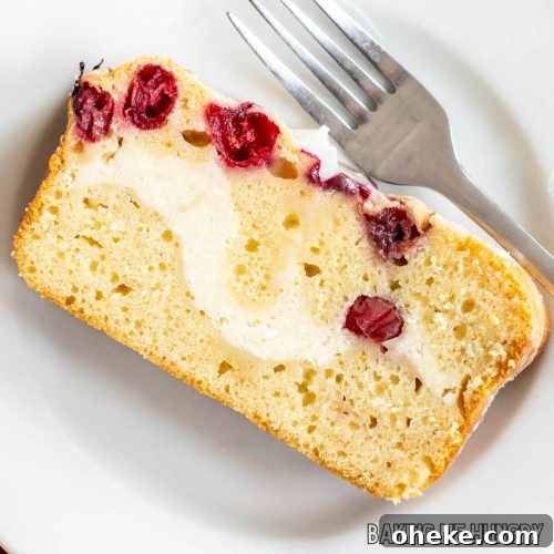 cranberry cream cheese bread sliced and on a white plate showing the cream cheese swirl close up