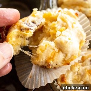 Savory Cheese & Bacon Breakfast Muffins That Impress 17 cheese and bacon muffins recipe shown as hand pulling muffin apart to show strings of cheese close up