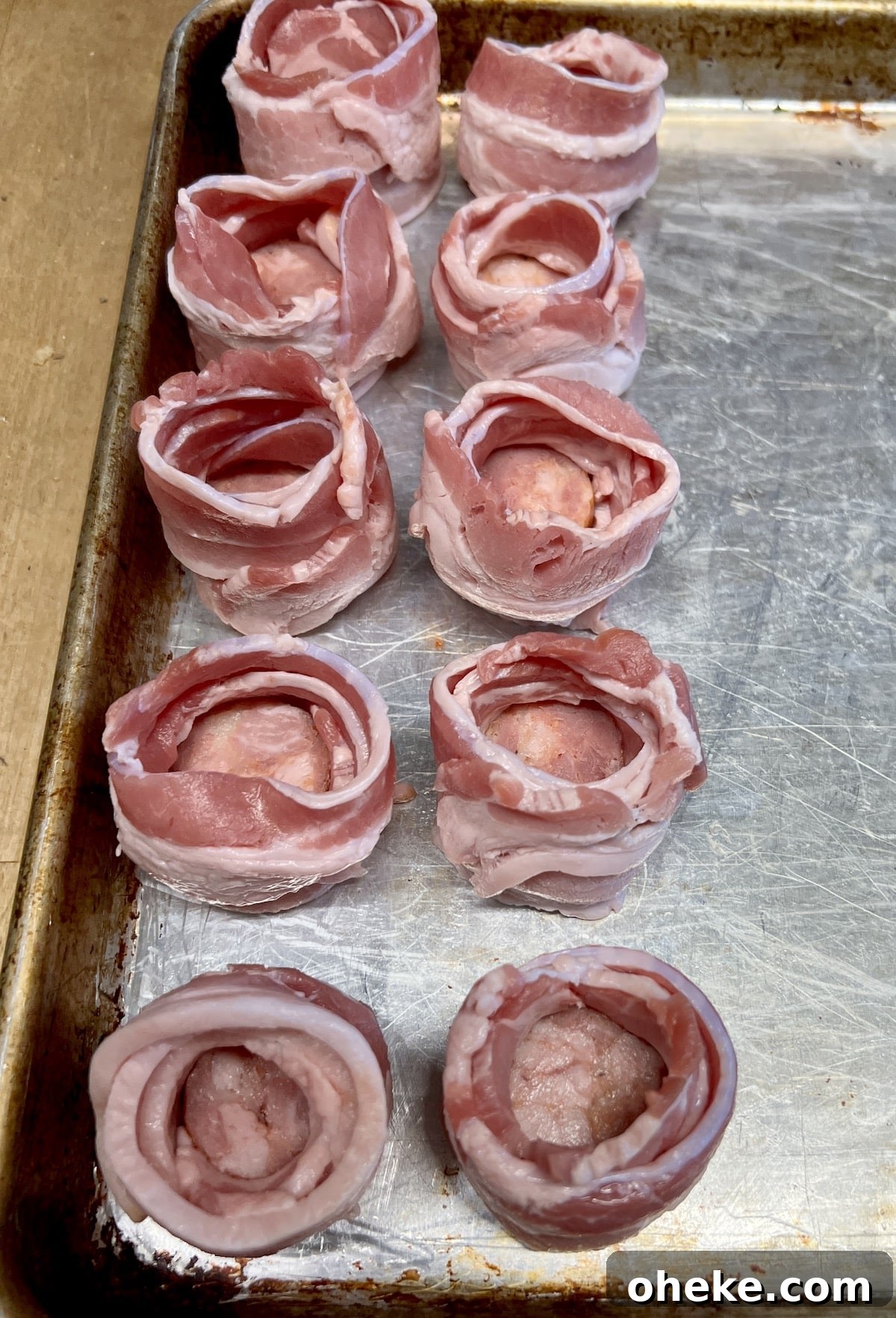 Sheet pan with bacon wrapped smoked sausage slices.