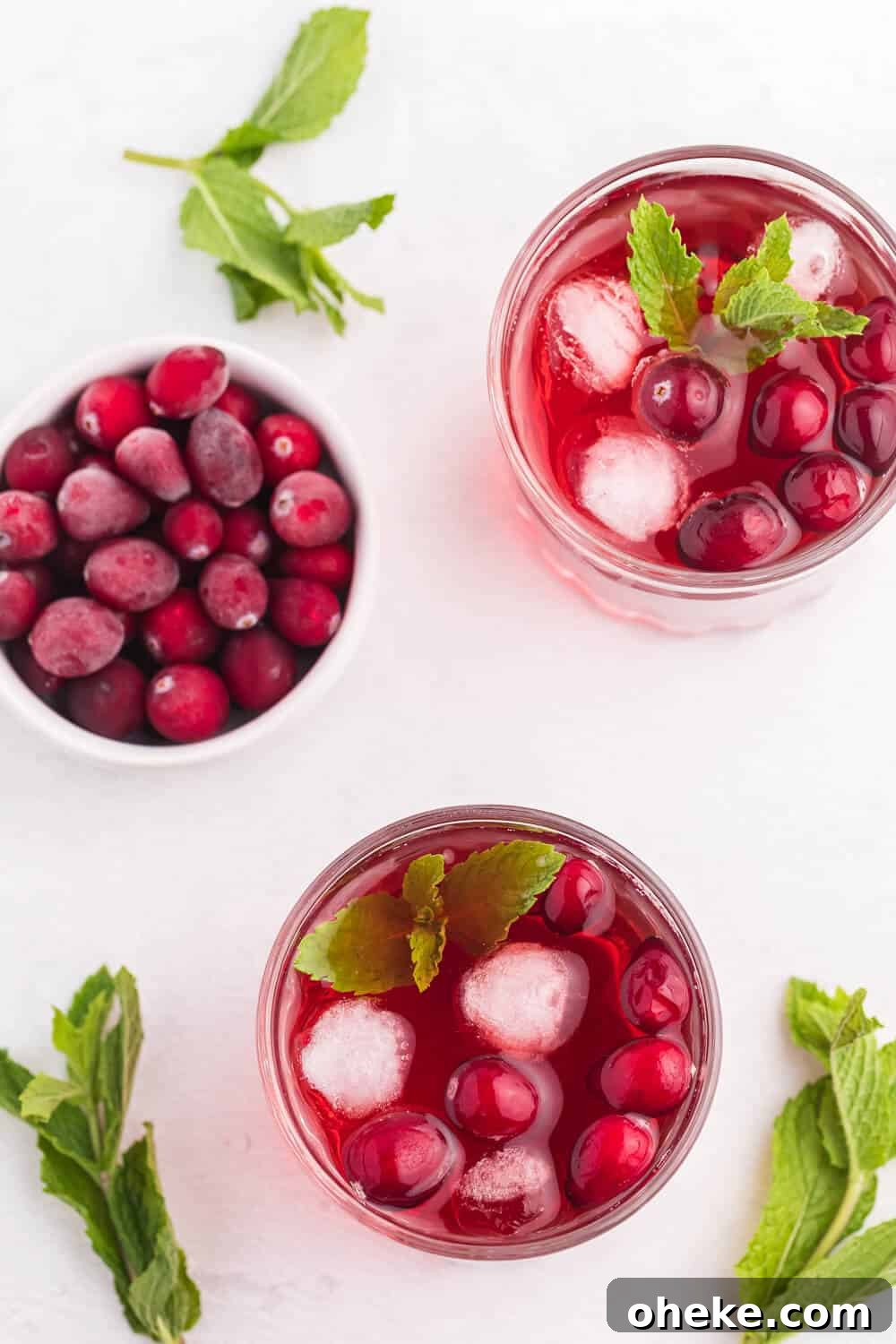 Glasses of the recipe on a white surface with mint leaves.