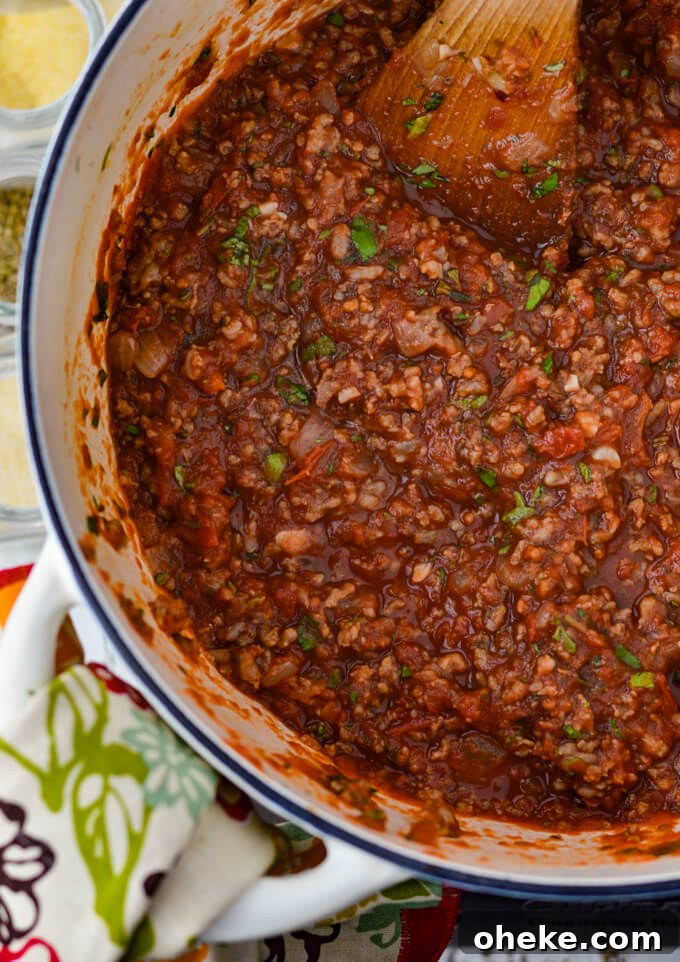 Slow-Cooker Lasagna Recipe for Tender, Cheesy Layers 7 A white Dutch oven holds spaghetti sauce for lasagna. A colorful napkin sits next to the pot.