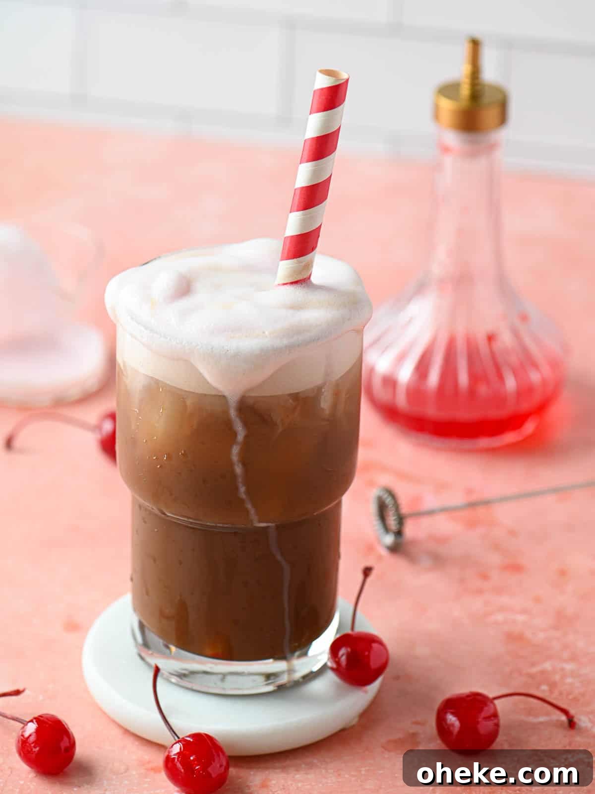Cherry Americola: Refreshing Cherry-Flavored Coffee Drink 2 A cherry americola drink with cherry cold foam dripping down in a clear glass.
