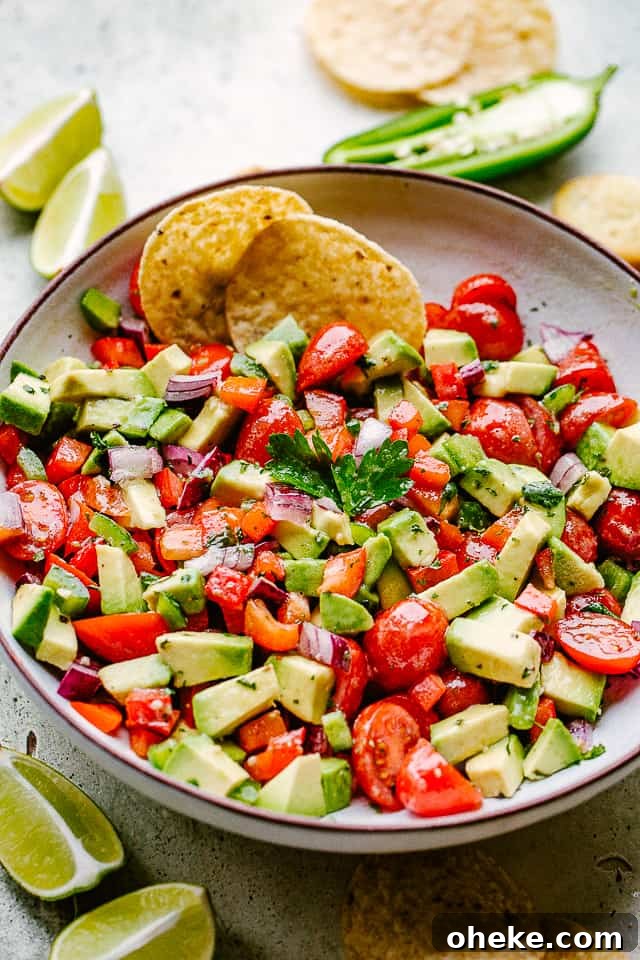 This avocado salsa is a next-level Cinco de Mayo recipe! It's creamy, chunky, and 100% addictive. It's like a flavor party in one bowl! avocado salsa served with tortilla chips and lime wedges