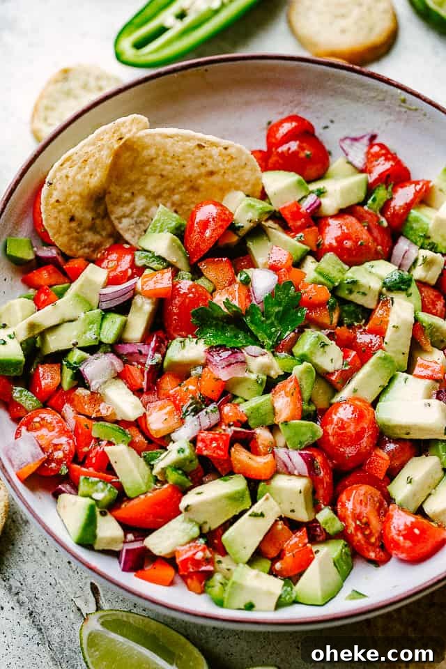 This avocado salsa is a next-level Cinco de Mayo recipe! It's creamy, chunky, and 100% addictive. It's like a flavor party in one bowl! bowl filled with chopped tomatoes, chopped avocado, and tortilla chips