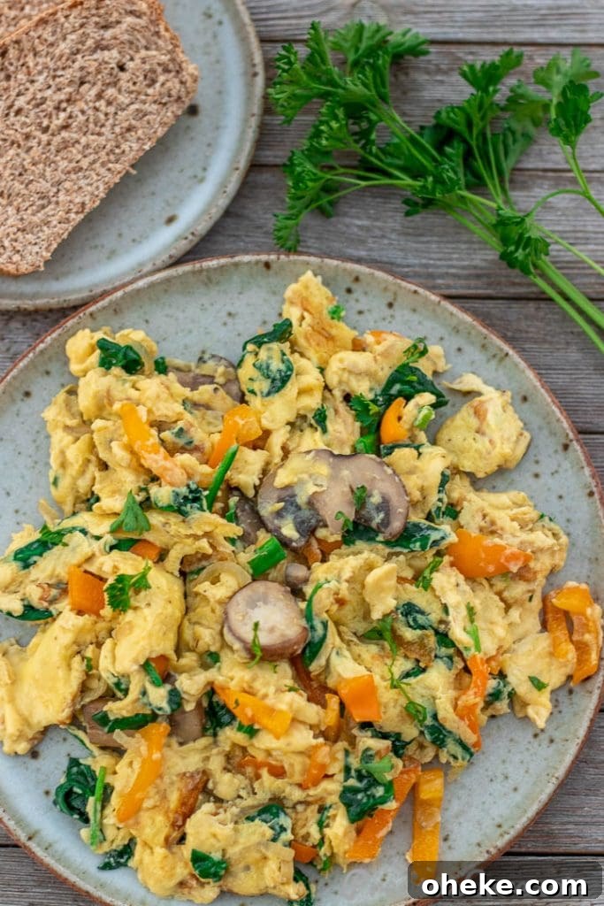 Scrambled Eggs with Vegetables on a plate with whole wheat toast on the side