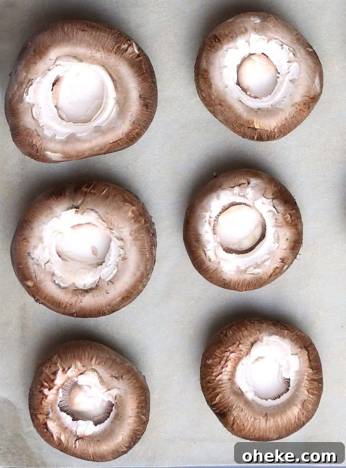 Six mushrooms on a cookie sheet ready to be stuffed.