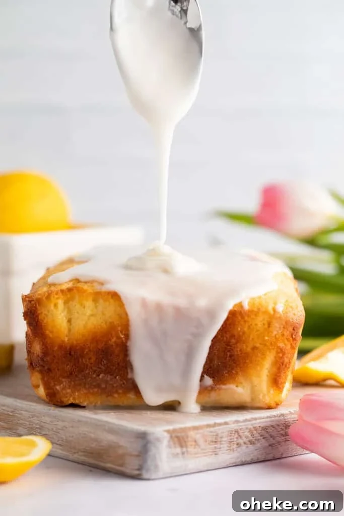 Ultimate Gluten-Free Lemon Cake Recipe — Moist & Zesty 3 Thick lemon glaze being poured over a gluten-free lemon pound cake loaf with tulips in the background.