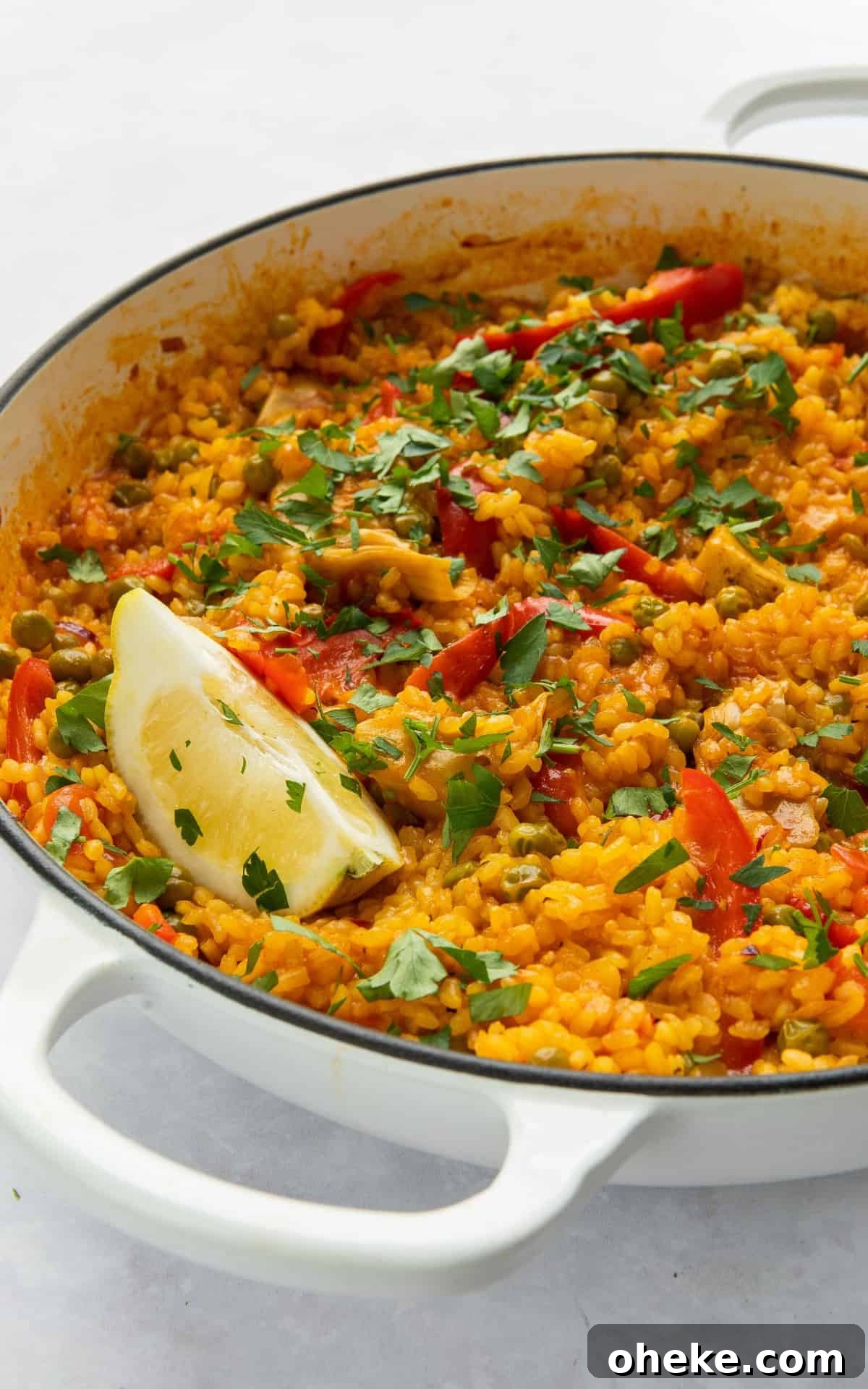 Paella in large white shallow dish with wedge of lemon. 