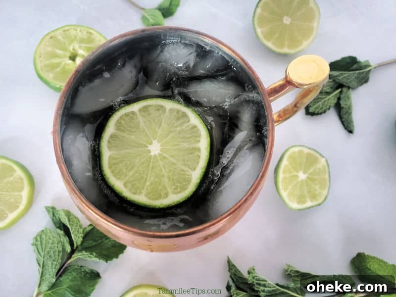 Irish Mule Cocktail & Mocktail Recipe with Video Guide 4 Looking down into an Irish Mule Cocktail in a copper mule mug with a lime wheel garnish surrounded by limes and mint sprigs