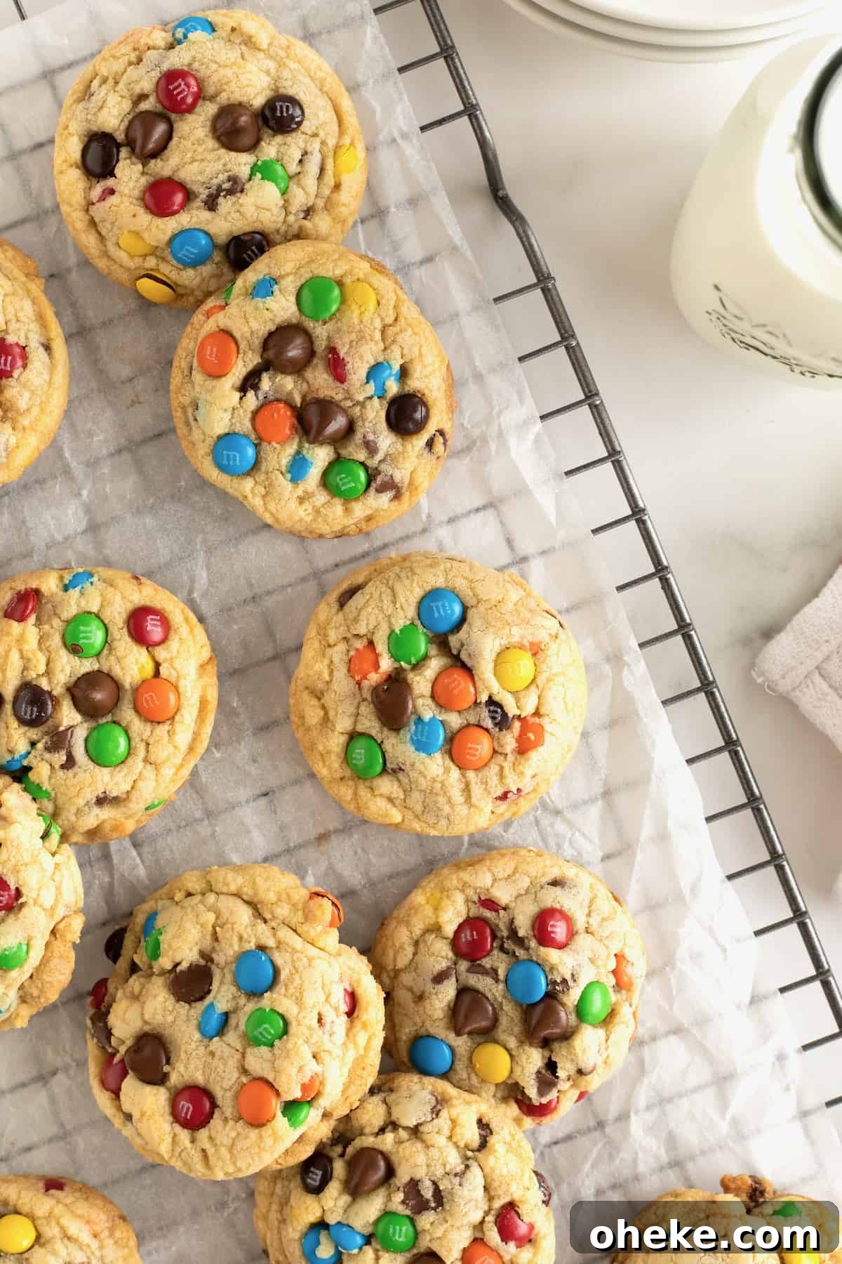 Baked M&M chocolate chip cookies on a parchment lined cooling rack.