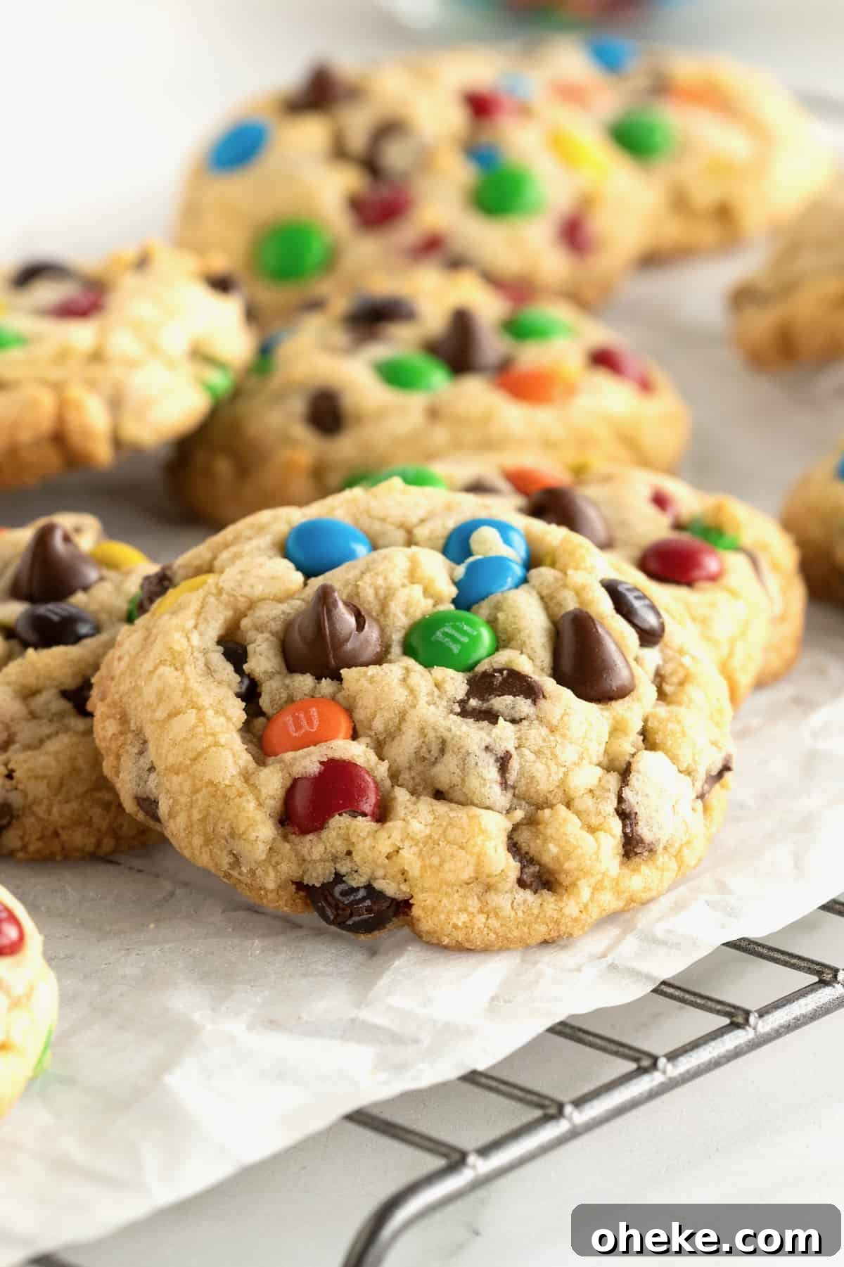 Baked M&M chocolate chip cookies on a parchment lined cooling rack.