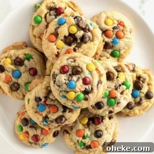 A white plate with a pile of cookies with M&Ms and chocolate chips in them.