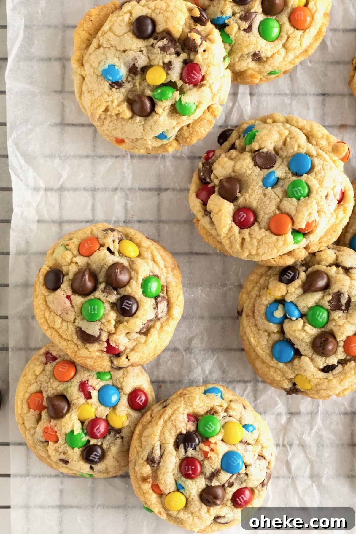 Baked M&M chocolate chip cookies on a parchment lined cooling rack.