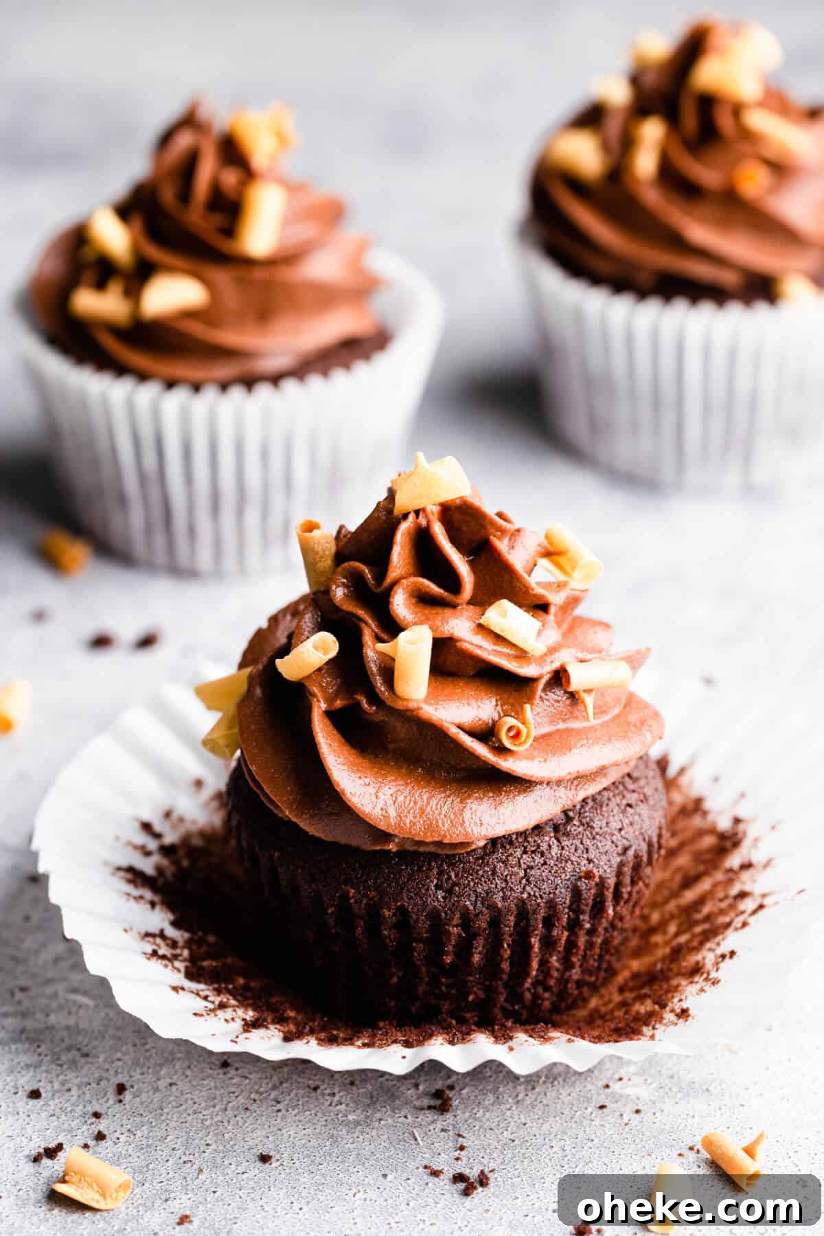 close up at a chocolate cupcake with buttercream unwrapped from its paper case