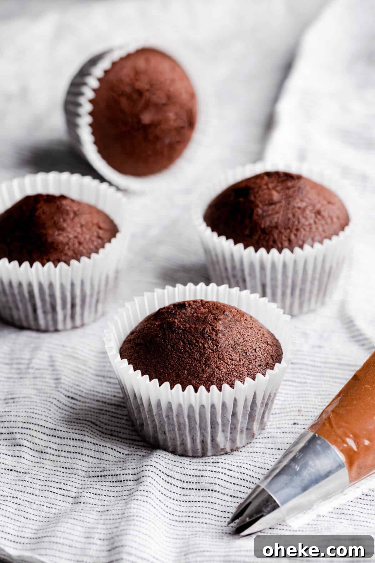 side angle photo of 4 small batch chocolate cupcakes in paper cases