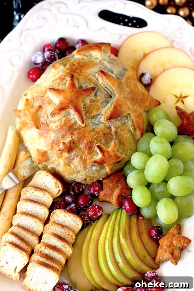 Baked Brie en Croûte with Cranberries and Puff Pastry 3 Overhead view of Baked Brie with Cranberries served with fruit and crackers.