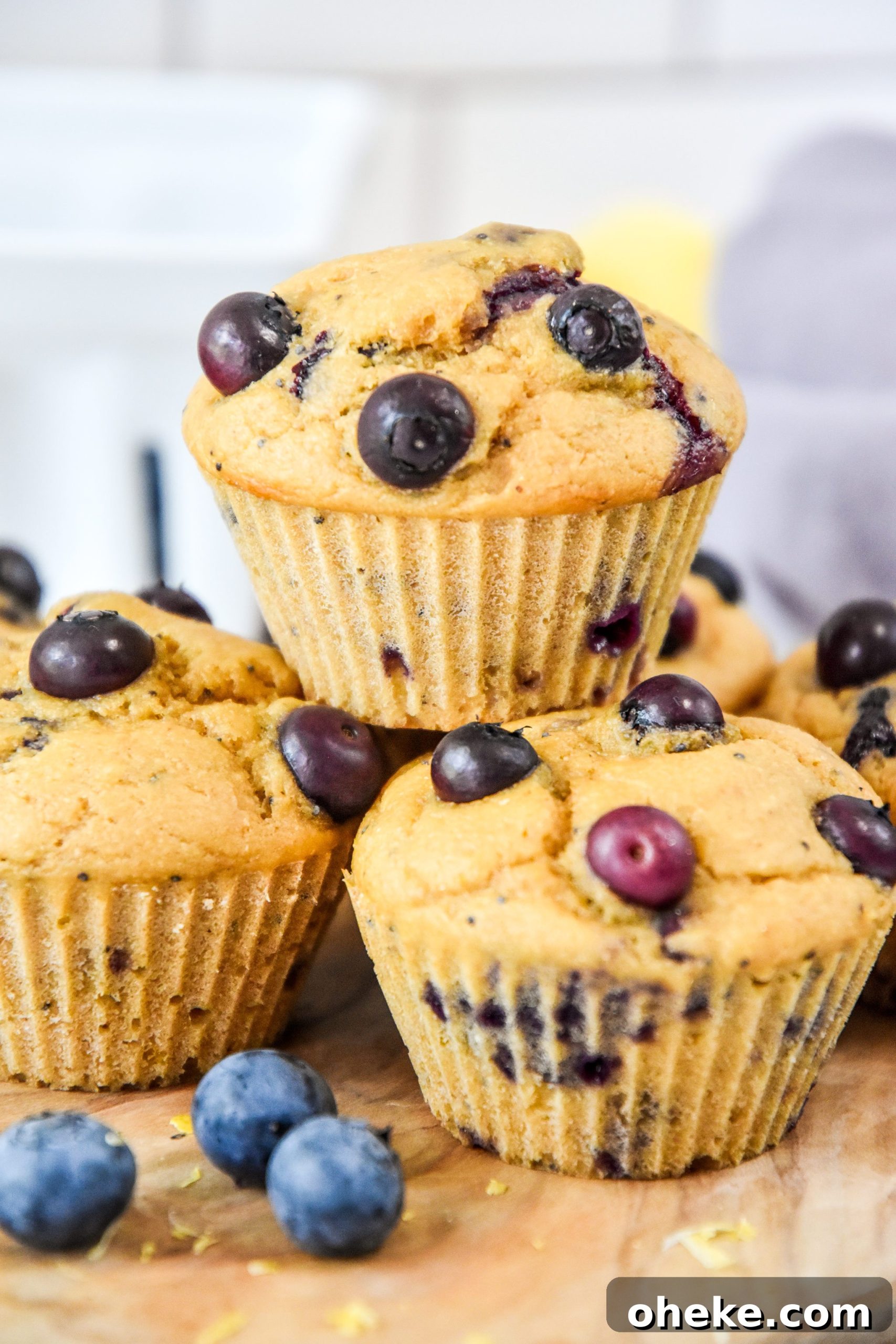 muffins stacked on a cutting board with blueberries.