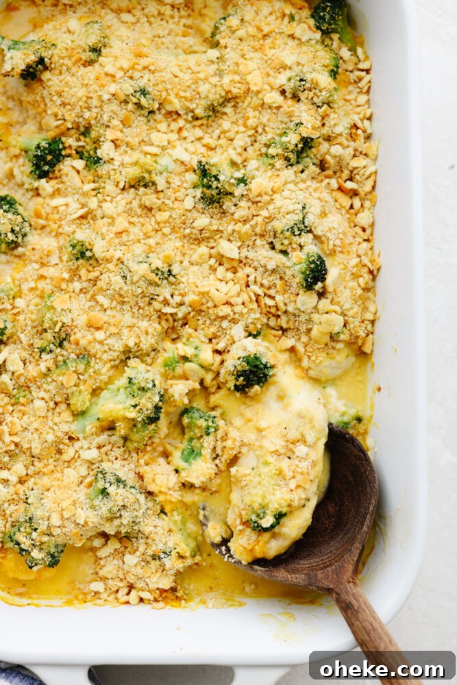 Comfort food at its finest, this broccoli cheddar chicken will fill you right up! Insanely delicious and straightforward to make, this is a dinner your entire family will go crazy over! A casserole dish with a wooden spoon serving some broccoli cheddar chicken.
