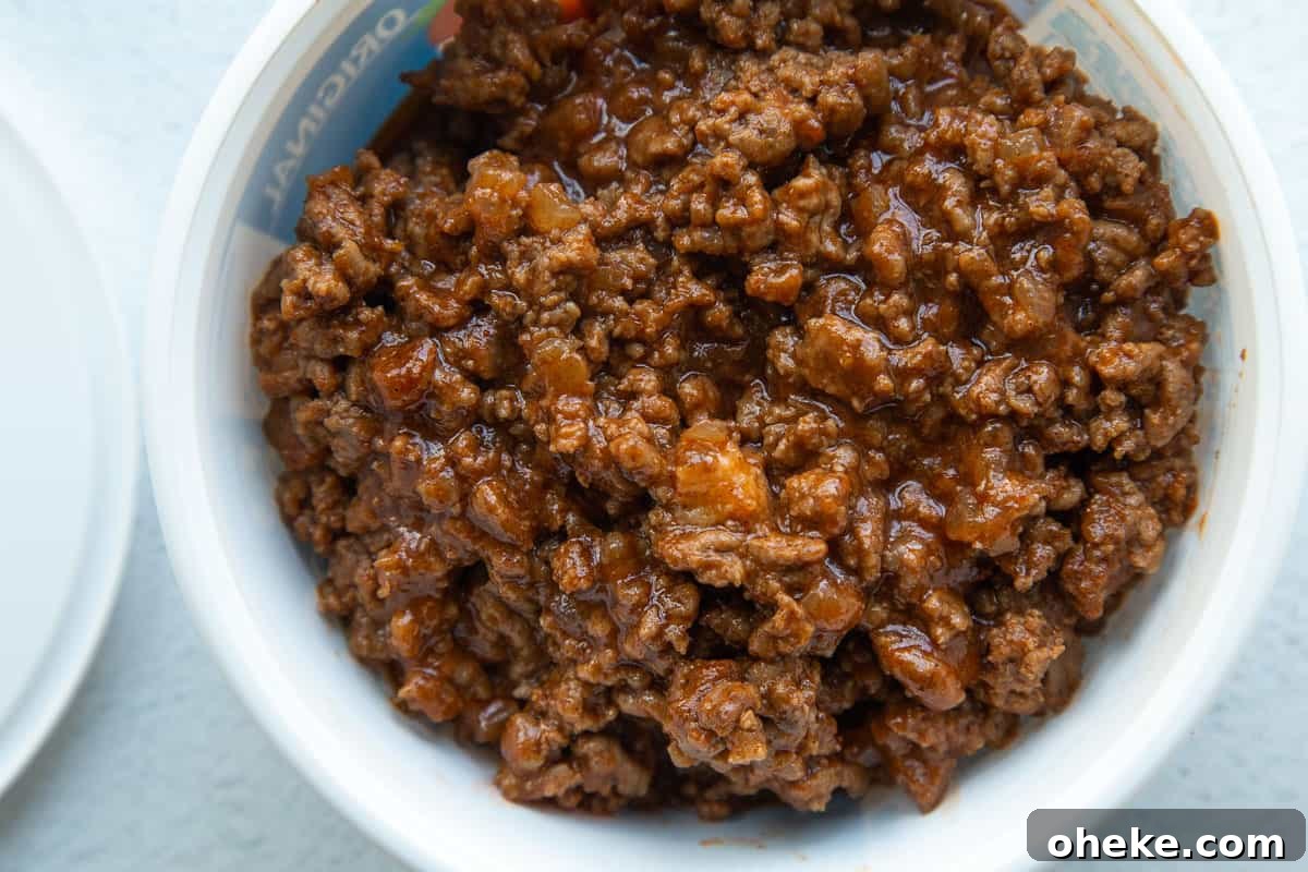 sloppy joe meat in a white plastic container next to a lid.