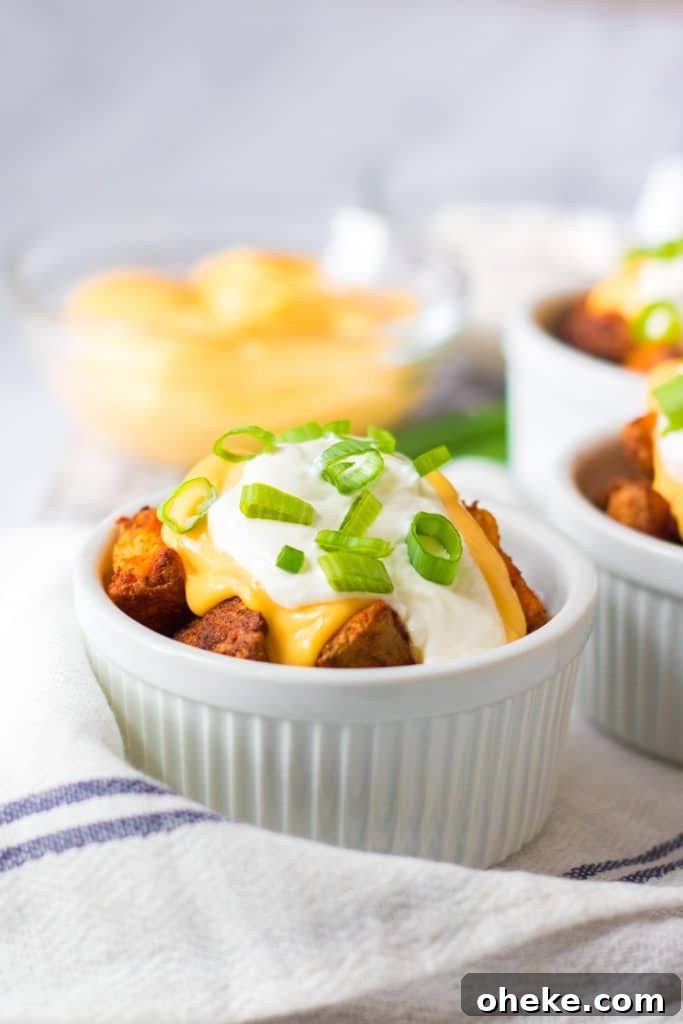 Air Fryer Cheesy Fiesta Potatoes — Taco Bell Copycat Recipe 2 cheesy air fryer potatoes in a white ramekin