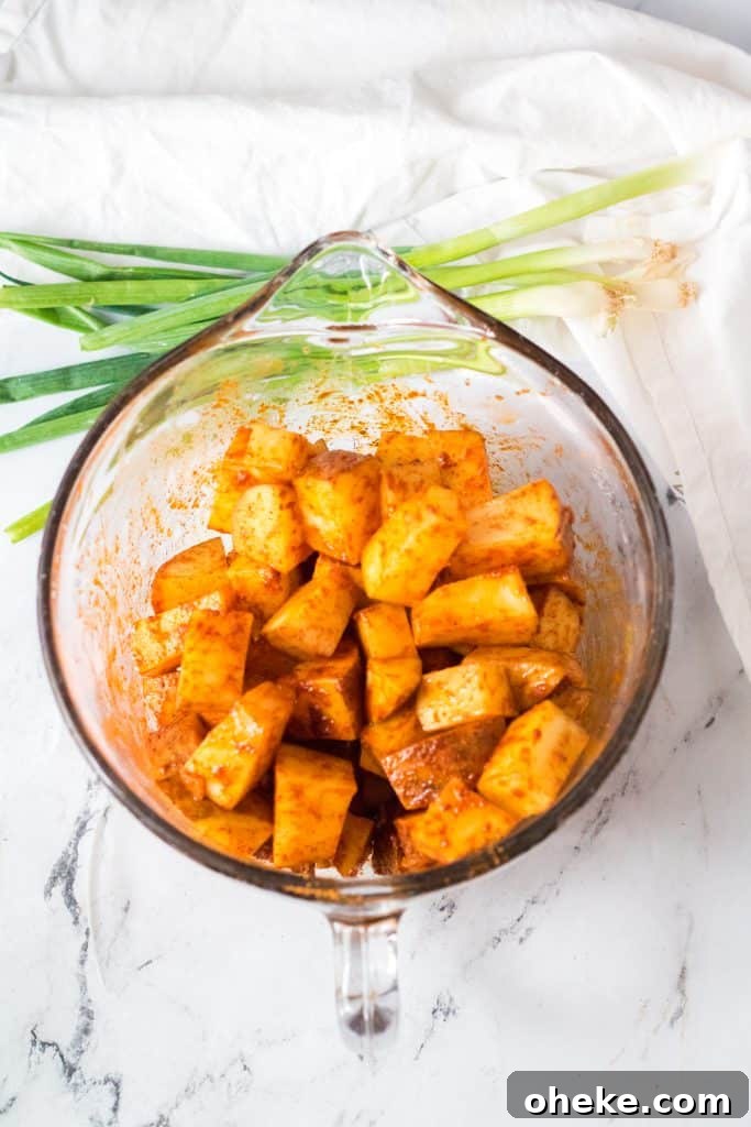 Air Fryer Cheesy Fiesta Potatoes — Taco Bell Copycat Recipe 5 seasoned diced potatoes in a large measuring glass bowl