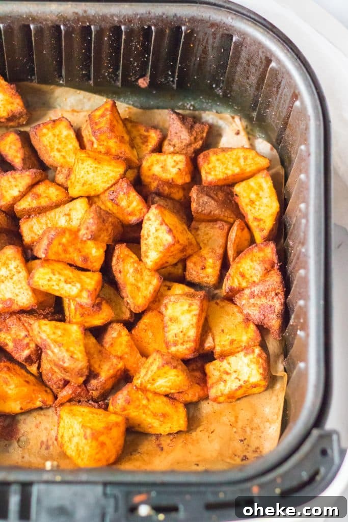 Air Fryer Cheesy Fiesta Potatoes — Taco Bell Copycat Recipe 6 cooked fiesta seasoned potatoes in the basket of an air fryer