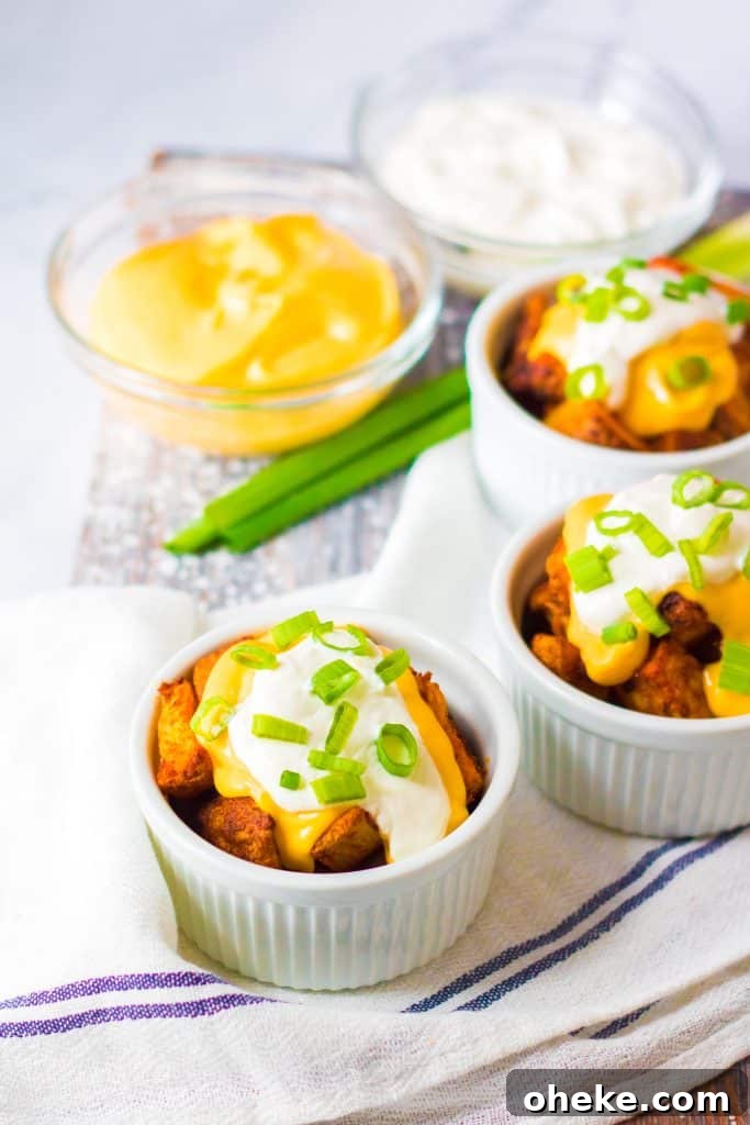 Air Fryer Cheesy Fiesta Potatoes — Taco Bell Copycat Recipe 8 cheesy fiesta potatoes topped with sour cream and sliced green onions in small white ramekins