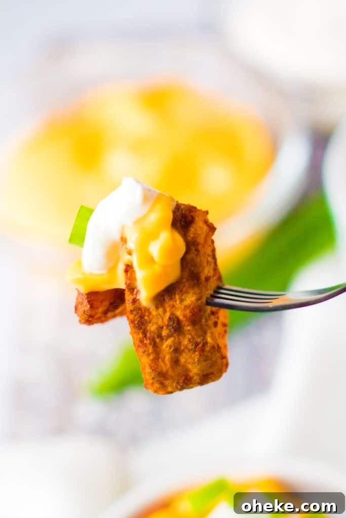 Air Fryer Cheesy Fiesta Potatoes — Taco Bell Copycat Recipe 10 a silver fork holding up a bite of cheesy fiesta potatoes