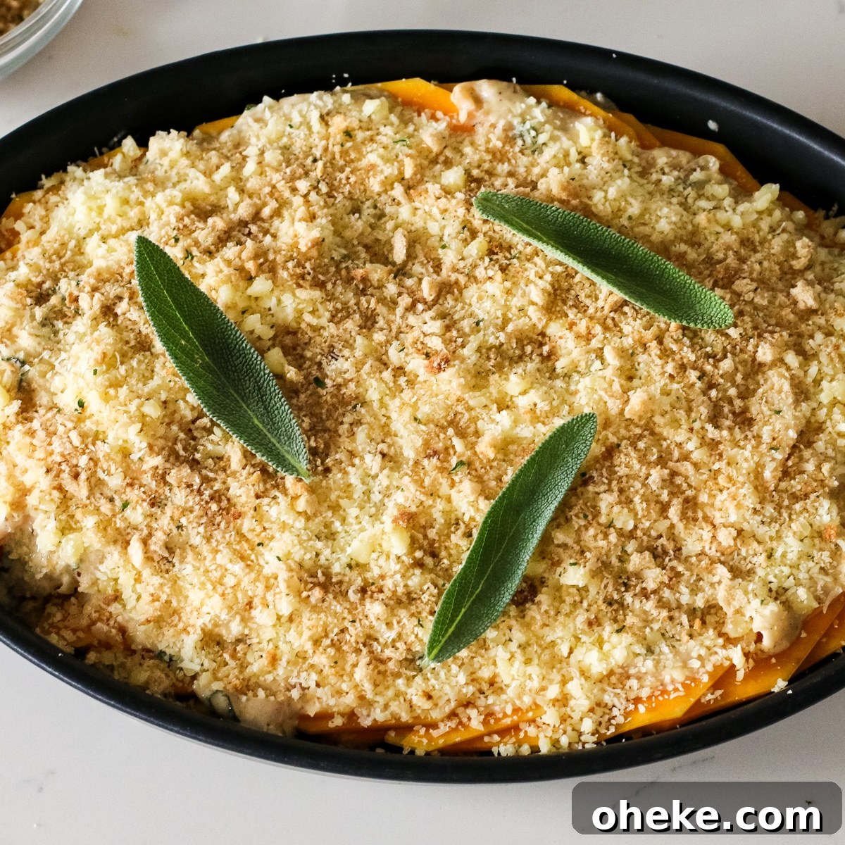 carmalized onion sauce covering the squash slices with bread crumbs on top, in a baking dish.