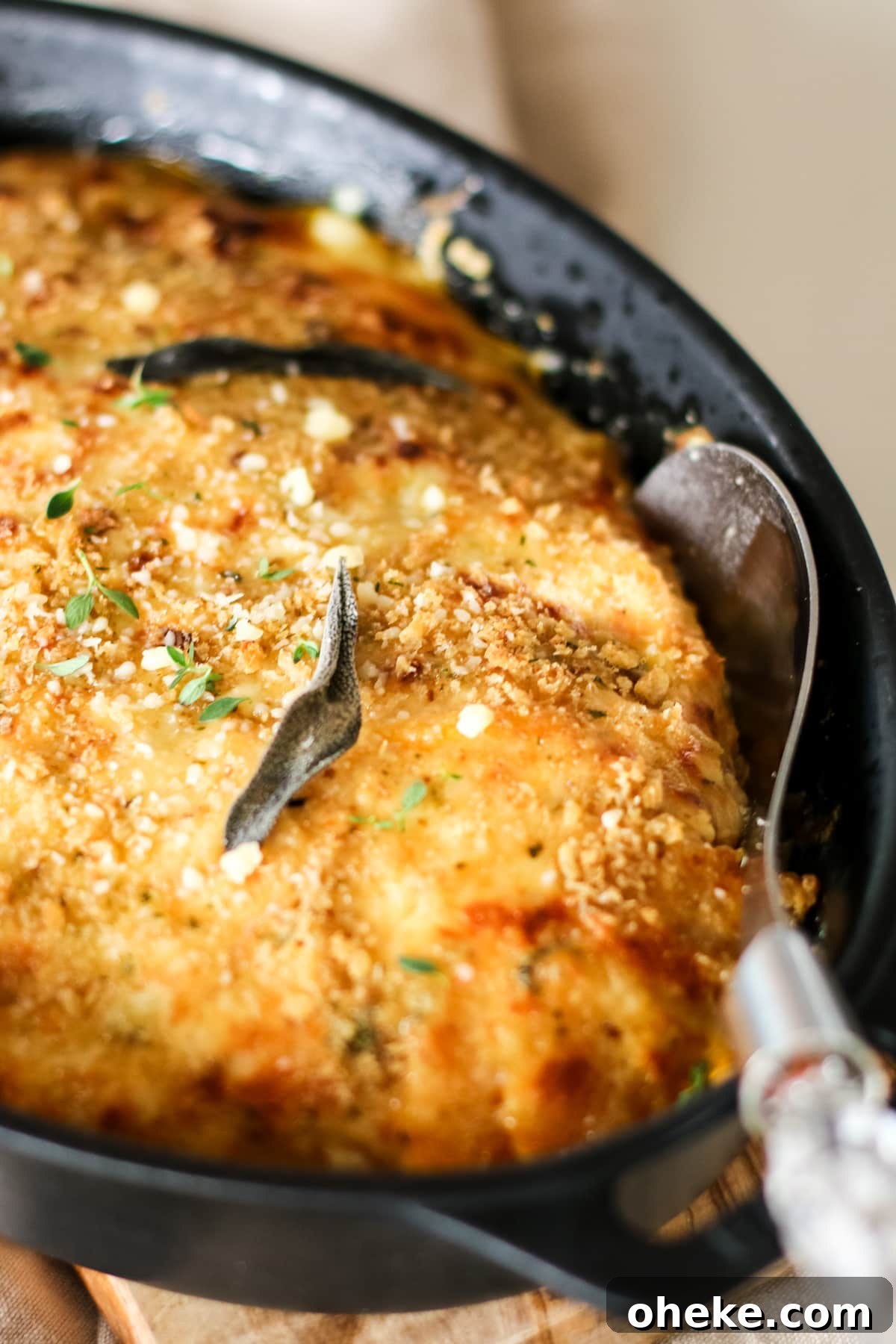 close up of butternut squash gratin in baking dish with serving spoon.
