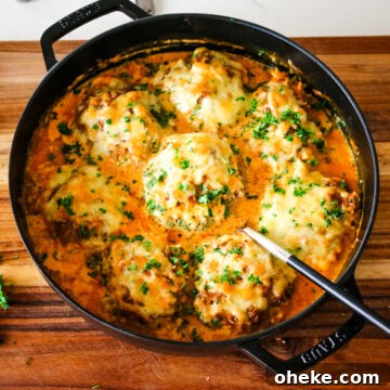 stuffed bell peppers in a creamy tomato sauce in a deep dish pan.