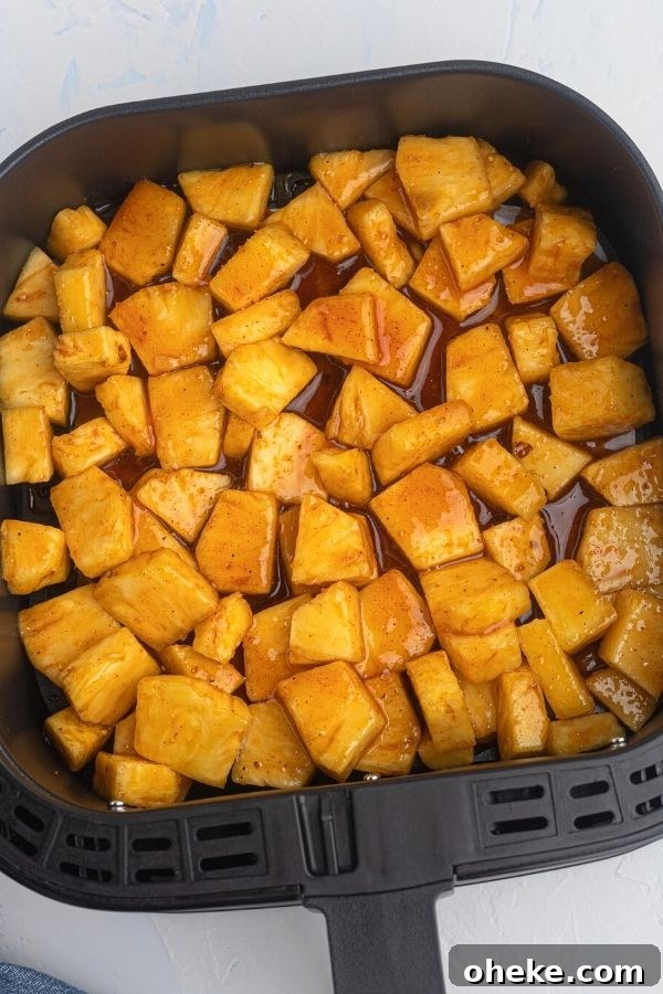 Juicy golden pineapple in the air fryer basket before being cooked in honey and bbq sauce.