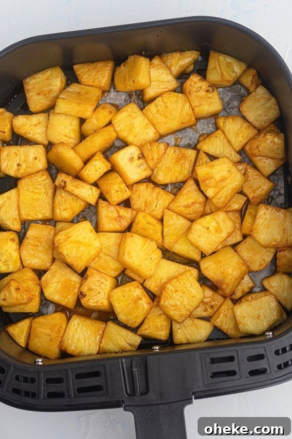 Juicy golden pineapple in the air fryer basket after being cooked in honey and bbq sauce. 