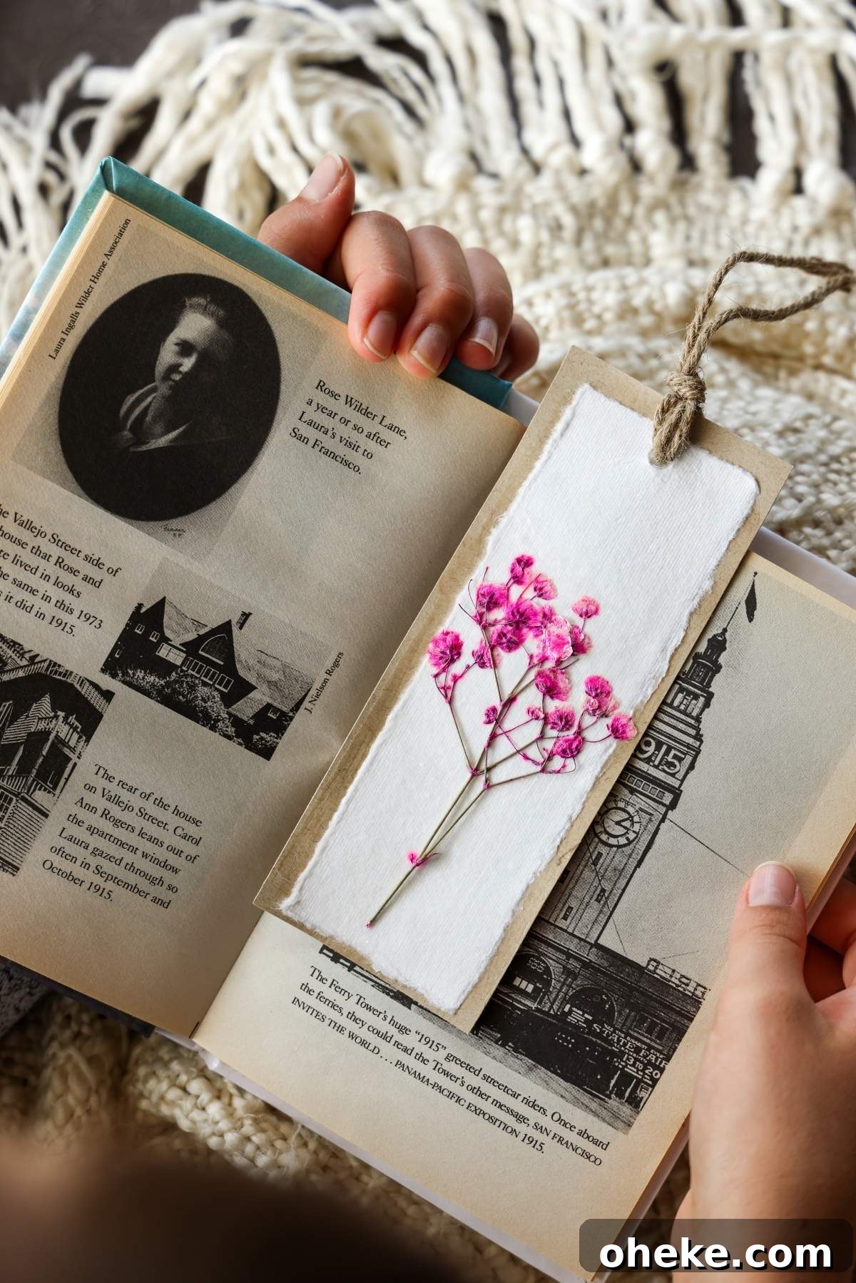 DIY Pressed Flower Bookmarks: Step-by-Step Craft Tutorial 6 Hands hold an open book with historical images and text, accompanied by a charming pink pressed flower bookmark on white paper, adding a touch of DIY elegance.