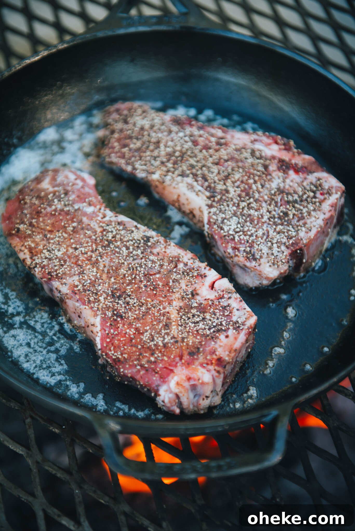 Steaks in hot skillet over campfire.