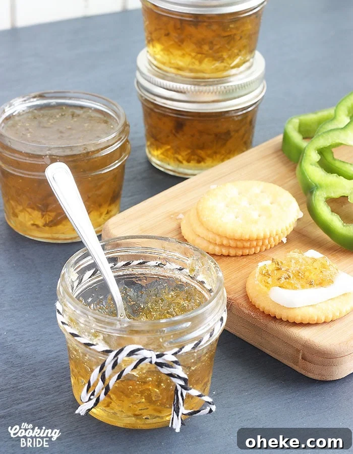 Sweet and Spicy Pepper Jelly Recipe for Preserving Peppers 2 small jelly jar of pepper jelly with crackers, fresh pepper slices and jelly jars in the background