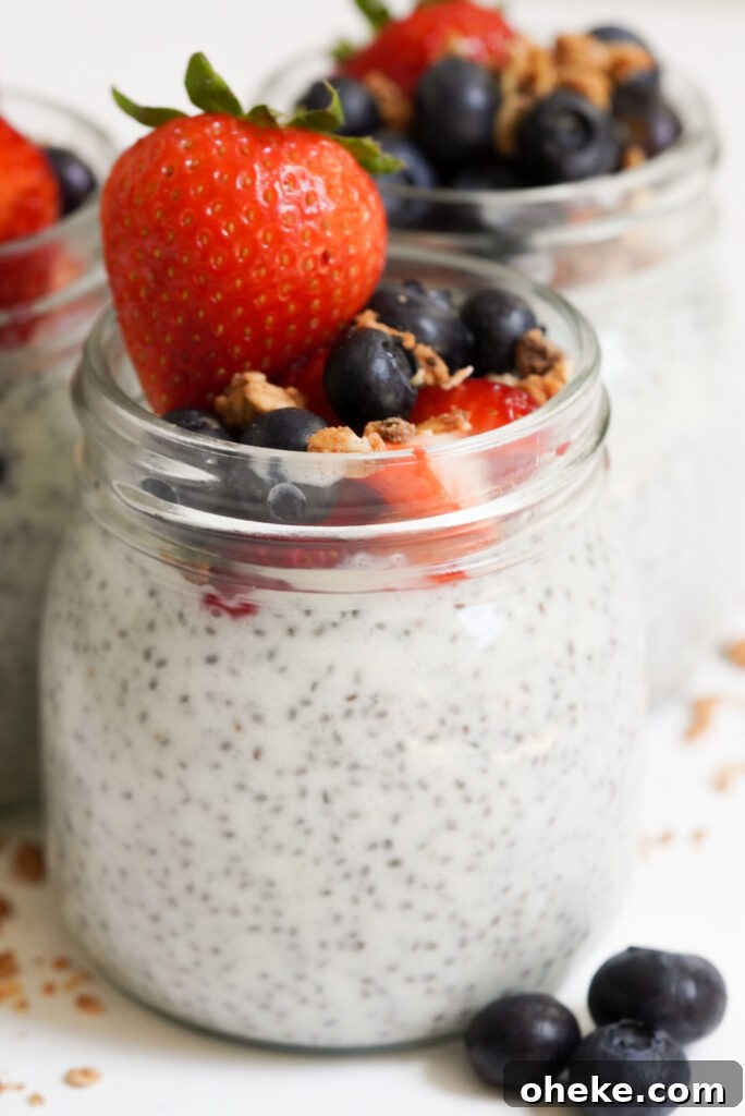 High-Protein Chia Pudding Recipe for Muscle Fuel 12 3 jars of chia pudding with protein powder that have been topped with blueberries, chopped strawberries, granola, and a whole strawberry each.