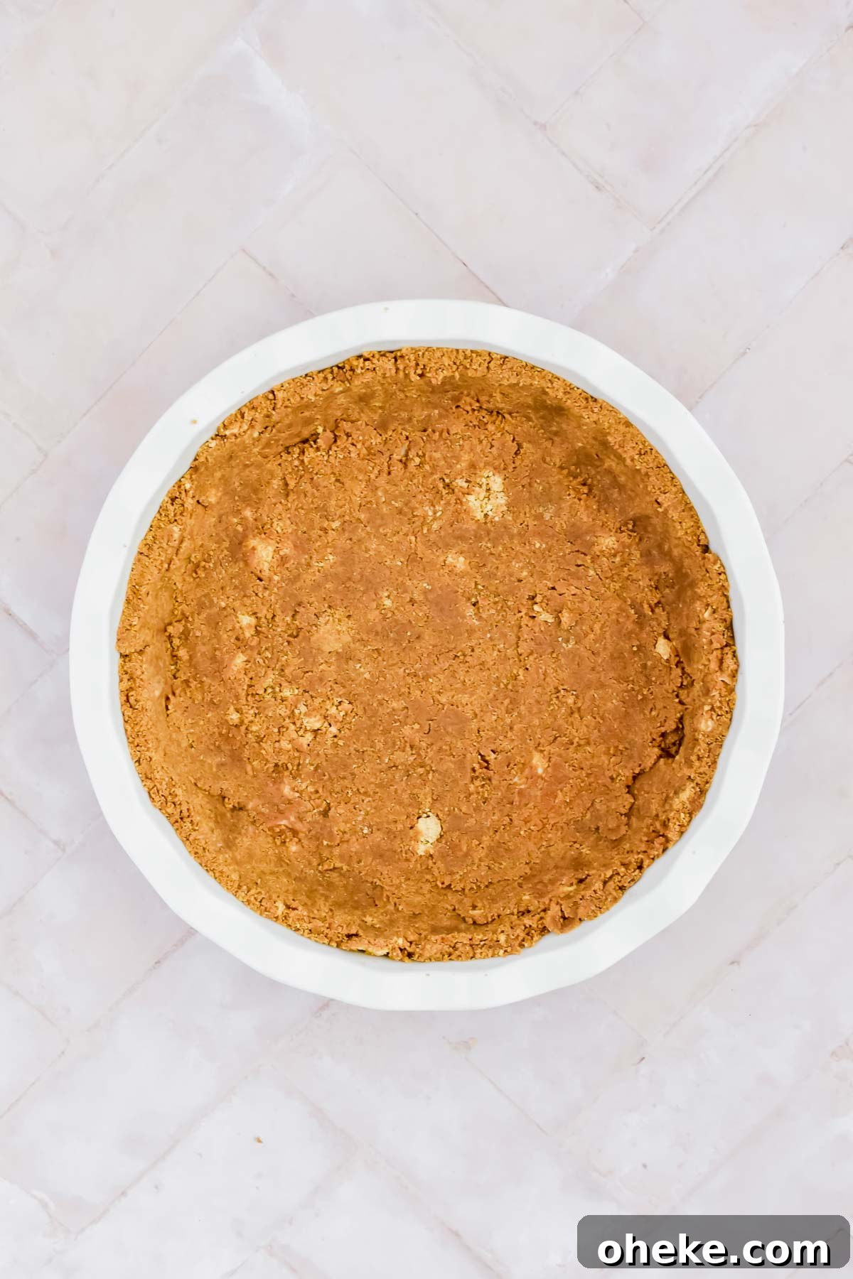 Tequila Lime Key Lime Pie Recipe with a Boozy Graham Cracker Crust 5 graham cracker crust in white pie dish on white background.