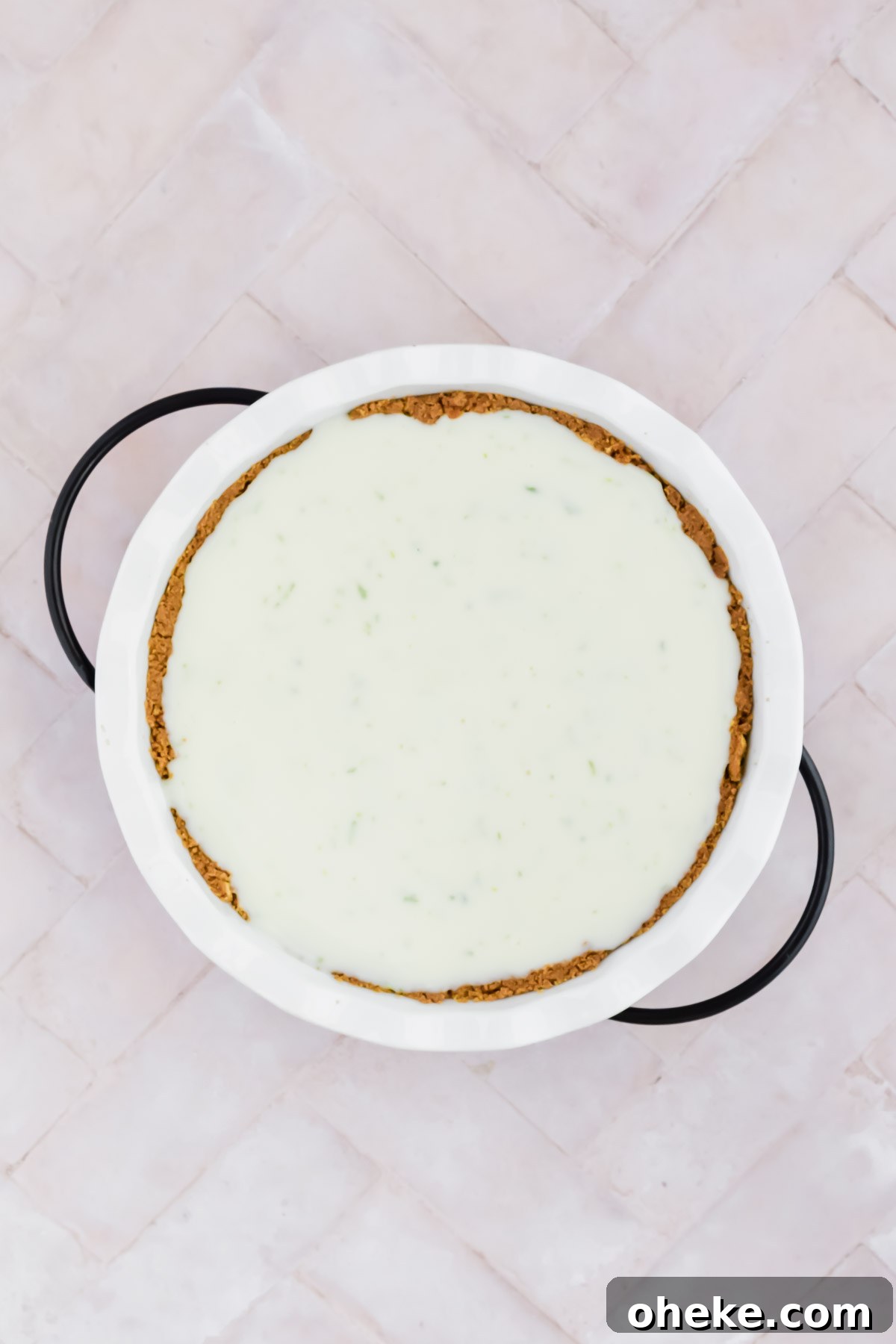 Tequila Lime Key Lime Pie Recipe with a Boozy Graham Cracker Crust 6 white pie dish filled with graham cracker crust and key lime pie filling on white background.