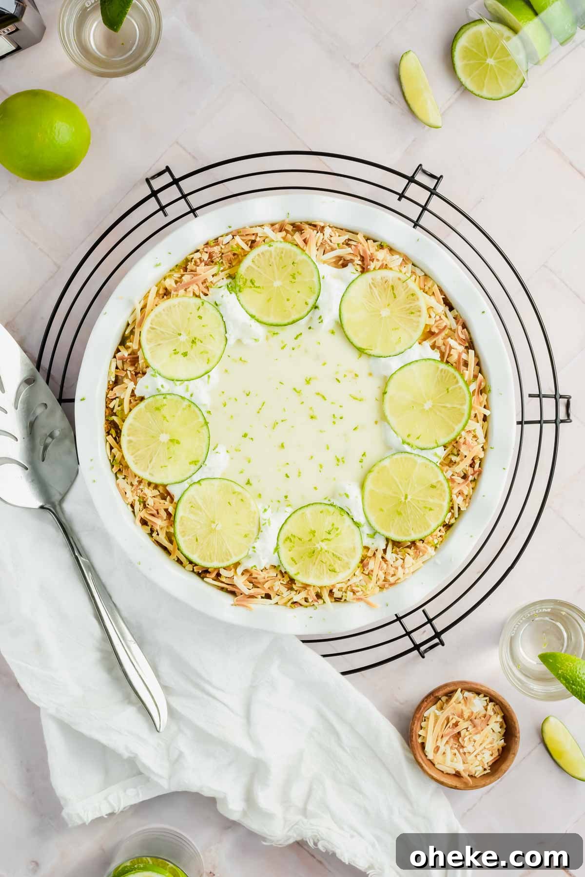 Tequila Lime Key Lime Pie Recipe with a Boozy Graham Cracker Crust 8 overhead shot of tequila key lime pie in white baking dish surrounded by extra recipe ingredients.
