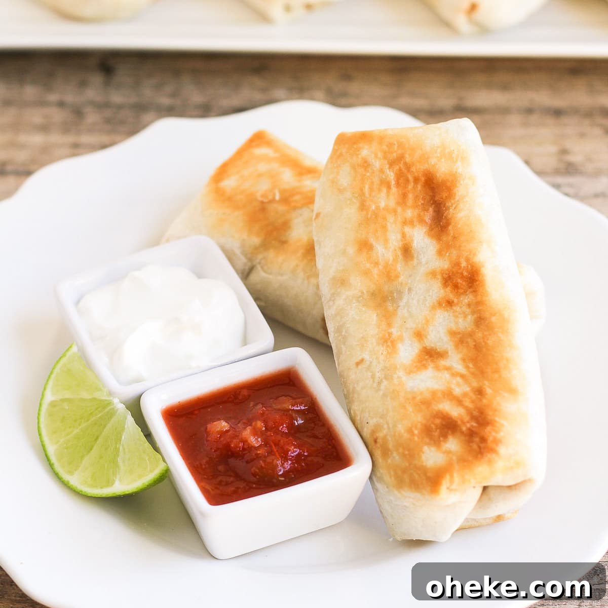 Easy and delicious Bean Chimichangas are filled with beans, cheese and ROTEL and they taste just like the ones at the restaurants! Two bean chimichangas on a plate with sour cream and salsa
