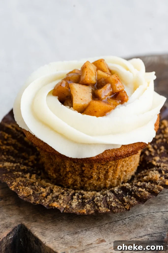 Apple Pie Cupcakes Recipe with Cinnamon Streusel 3 Single cupcake with wrapped folded down, topped with vanilla buttercream and apple pie filling.