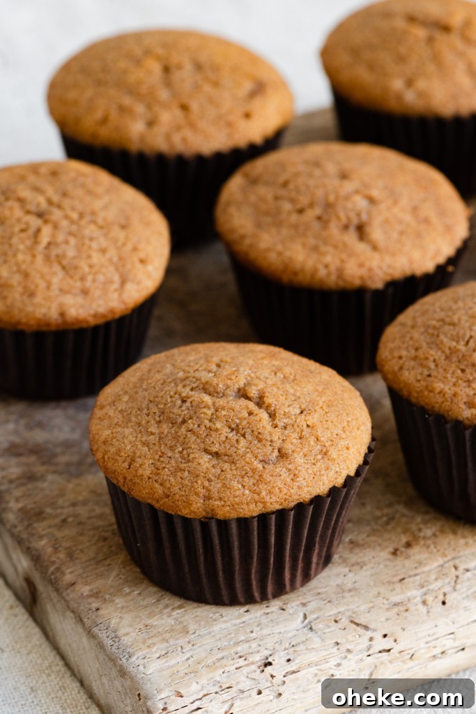 Apple Pie Cupcakes Recipe with Cinnamon Streusel 4 Unfrosted brown sugar cupcakes on a wooden cutting board.